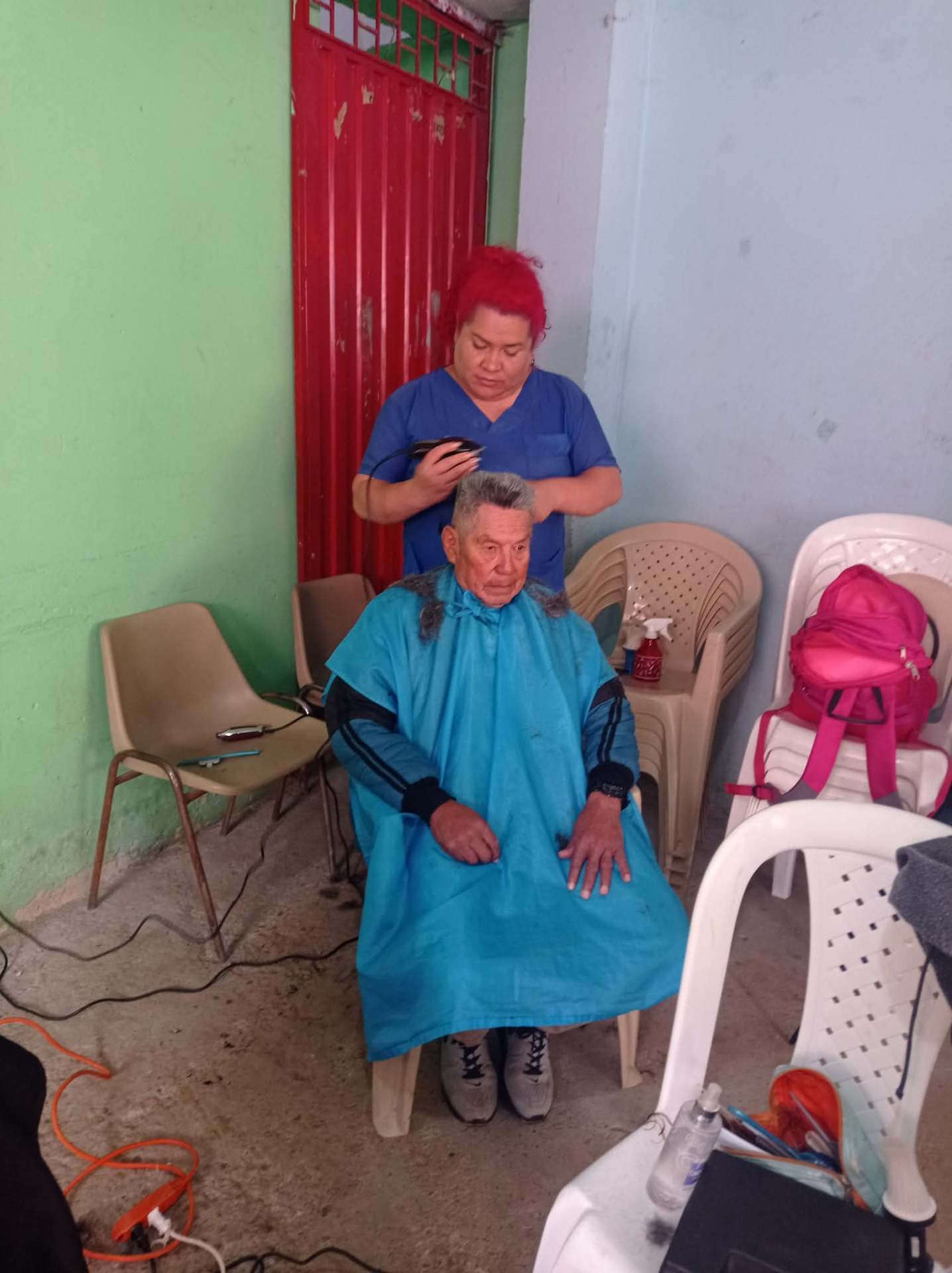 Voluntaria realizando un corte de cabello a un adulto mayor
