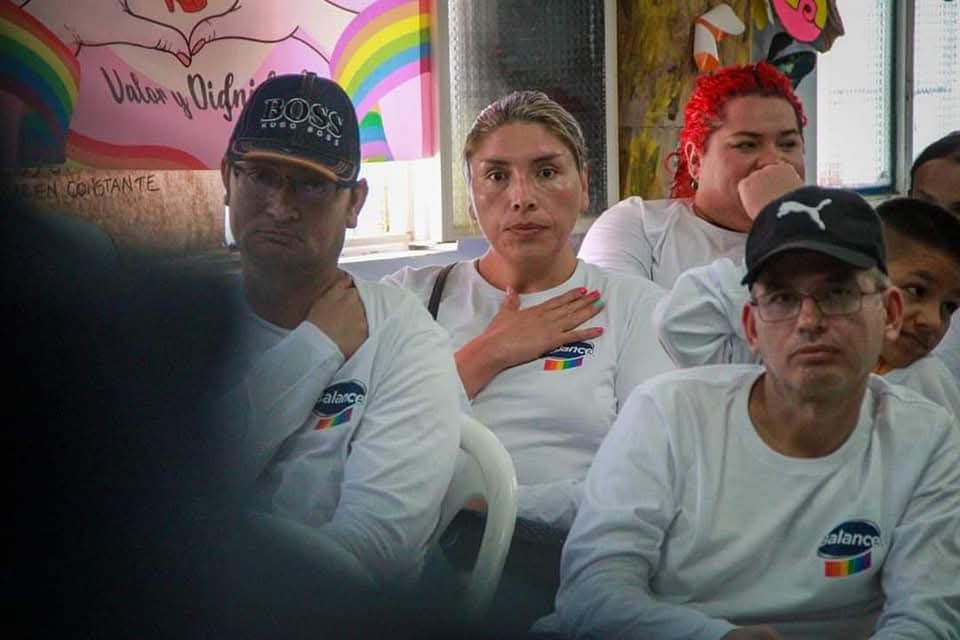 Encuentro comunitario con camisetas blancas frente al mural Valor y Dignidad
