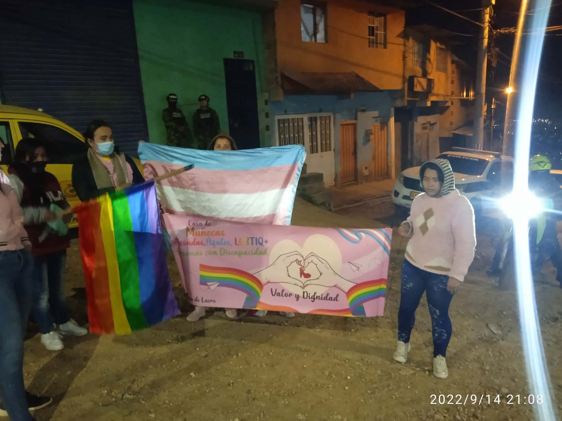 Marcha nocturna con bandera trans, bandera del arcoíris y pancarta de la fundación